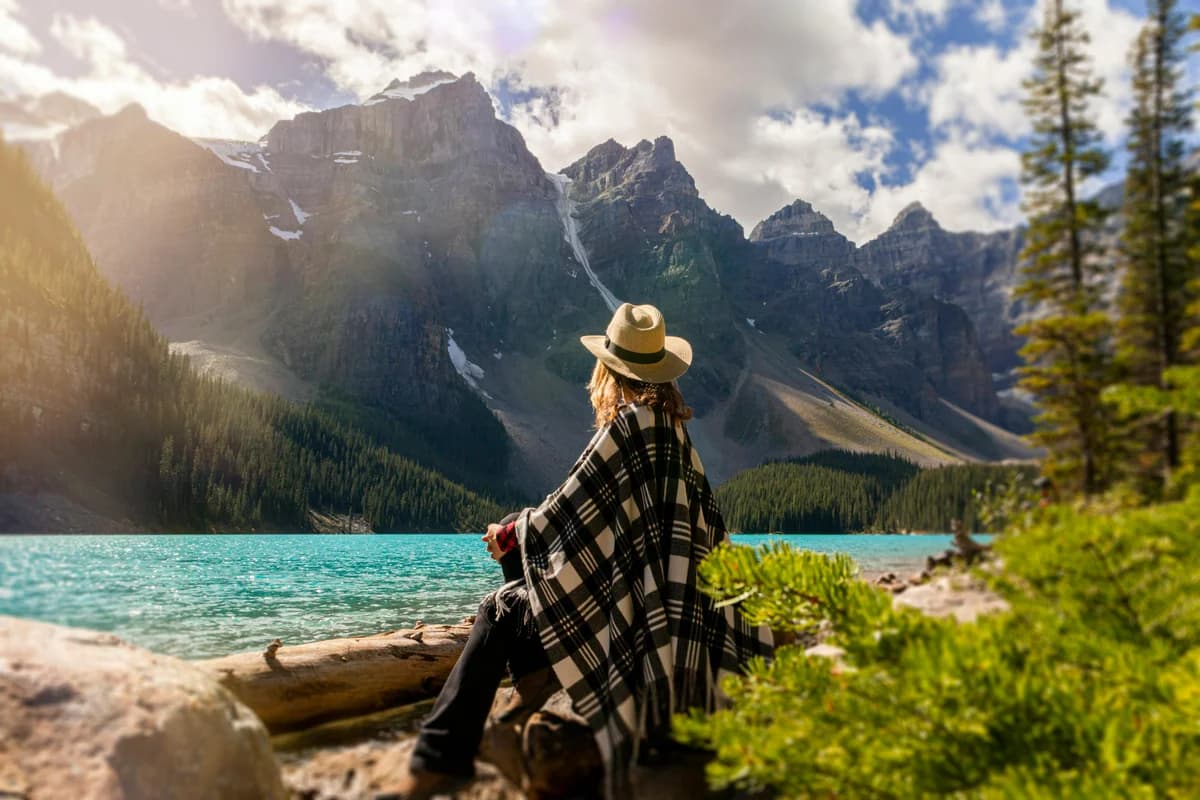 Young adult sitting peacefully by a mountain lake in Colorado, representing the calm confidence achieved through young adult therapy in Castle Rock